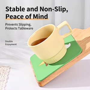 Sottobicchiere in silicone verde con tazza in ceramica gialla su vassoio in legno inclinato