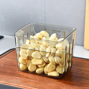 Transparent wall-mounted kitchen storage basket filled with fresh garlic on a wooden board