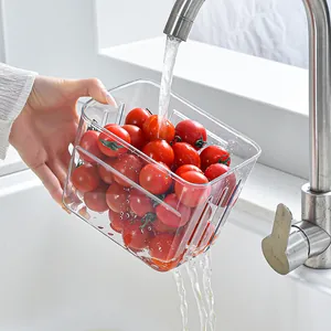 Clear transparent kitchen storage basket washing fresh cherry tomatoes under running tap water