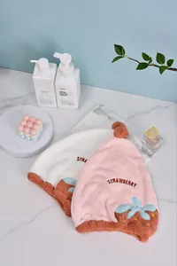 Vue détaillée des bonnets de séchage fraise rose et blanc avec texture douce et broderie.