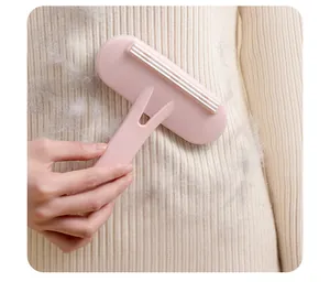 Detail view of the pink portable lint remover scraping fuzz off a knitted sweater fabric