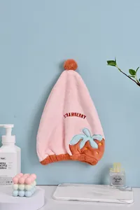 Bonnet de séchage fraise rose en microfibre sur un mur bleu clair
