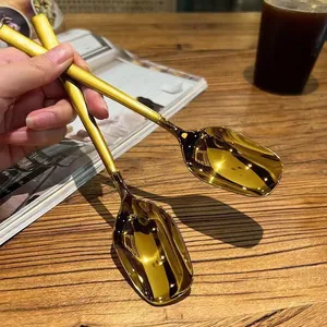 Elegant gold stainless steel lantern spoons for dessert and soup on wooden table
