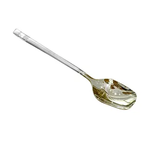 Close-up of a stainless steel dessert spoon with a golden finish and long handle