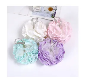 Macro view of four soft ruffled mesh bath sponges in pastel colors with pom-pom edges