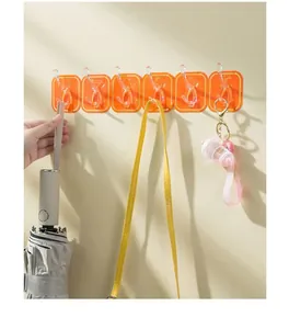 Wall-mounted row of six orange adhesive hooks holding an umbrella and a bag strap