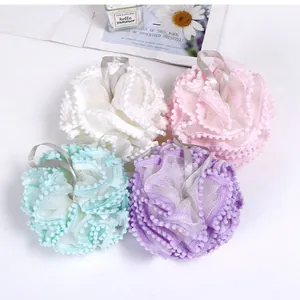 Set of four colorful mesh shower loofahs with pom-pom trim and hanging ribbons