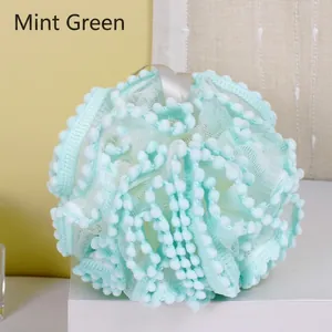 Mint green soft bath flower loofah sponge with textured edges on white pedestal