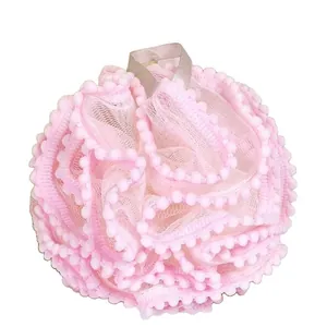 Soft pink mesh bath sponge ball with decorative pom-pom trim and a grey hanging loop