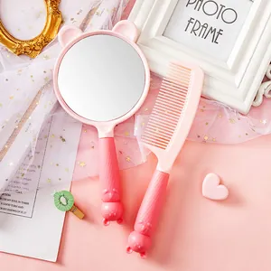 Close-up of cute pink cartoon bear-eared handheld vanity mirror and matching hair comb