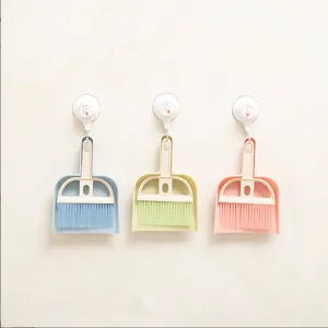 Detail showing mini dustpan and broom sets in blue, green, and pink hanging on wall