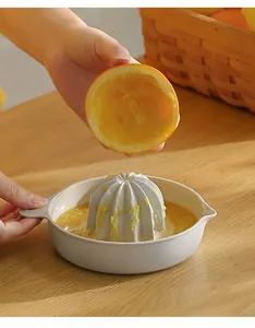 Manual orange juicer squeezer showing freshly pressed citrus juice in a beige bowl
