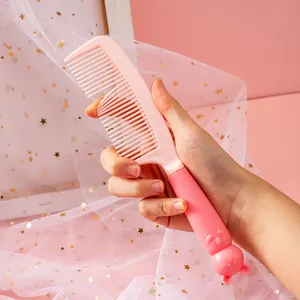 Close-up of a cute pink cartoon hair comb held in hand against starry lace fabric
