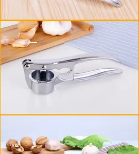 Manual stainless steel garlic press and nutcracker tool shown with fresh garlic and walnuts