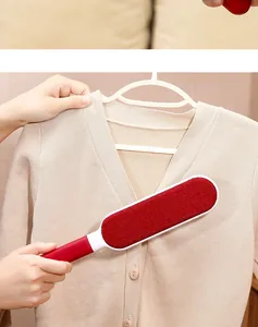 Close-up of red electrostatic lint remover brush cleaning a beige knitted sweater