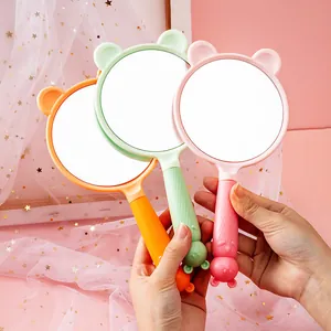 Close-up view of three portable cute cartoon handheld makeup mirrors in various colors