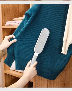 Detailed view of manual lint remover brush cleaning a blue knitted sweater