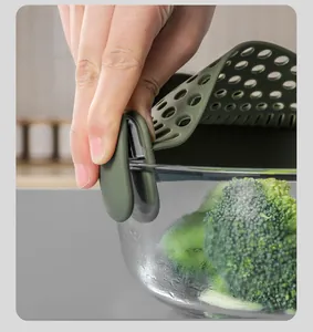 Close-up of a green silicone clip-on pot strainer securely attached to a glass bowl edge