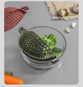 Detailed view of green silicone snap-on pot strainer filtering broccoli in glass bowl.