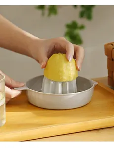 Close-up of manual lemon juicer being used with a fresh lemon on a wooden tray