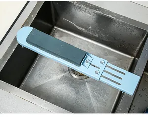Whetstone on a blue adjustable sink holder bridge over a stainless steel kitchen sink
