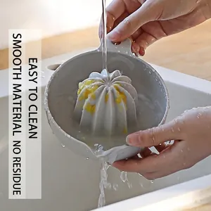 Grey manual citrus juicer being rinsed under water in a sink, easy-to-clean plastic squeezer