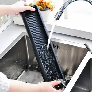 Vassoio scolapiatti nero per lavandino sciacquato sotto l'acqua corrente