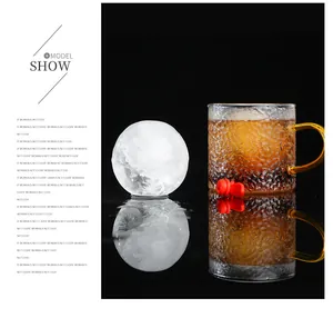 Gedetailleerd zicht op een ronde ijsbal en een getextureerd whiskyglas op een reflectie