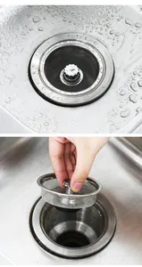 Detail view of a stainless steel kitchen sink strainer being lifted from a drain