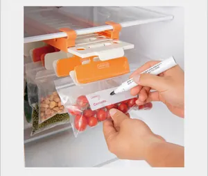Macro view of hands writing on a hanging refrigerator bag organizer with clips