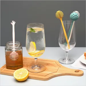 Multi-colored plastic honey dippers and stirrers for coffee and tea in a lifestyle setting.