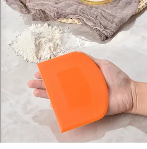 D-shaped orange plastic dough scraper held in hand for professional baking size reference