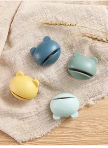 Detailed view of four colorful cartoon frog shaped mini manual knife sharpeners on linen cloth