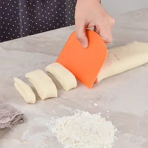Orange plastic dough scraper for baking and cake decorating in a home kitchen setting