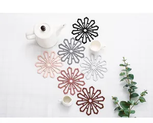 Sottopentola in silicone a forma di fiore in vari colori su una tovaglia bianca