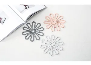Tre sottopentola in silicone a forma di fiore in grigio rosa e bianco su un tavolo ruvido