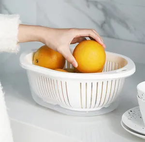 Detail view of a white plastic double-layer drain basket being used to store fresh oranges.