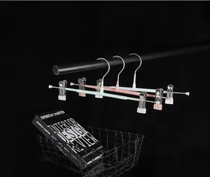 Set of three colored adjustable pants hangers with non-slip clips on a black rod.