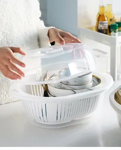 Detail of white double-layer colander with clear lid showing bowls and cutlery inside