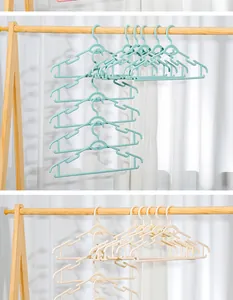 Close-up van lichtblauwe en beige plastic kledinghangers aan een houten droogrek