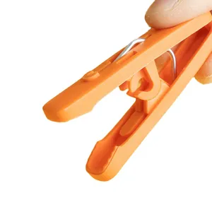 Durable orange plastic clothespin with strong metal spring for laundry drying