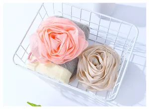 Elegant rose-shaped bath sponges in pink and beige colors inside a white basket