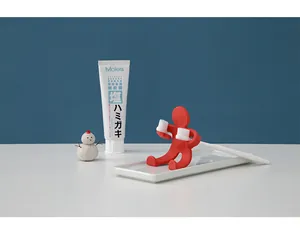 Detailed view of a creative red humanoid toothbrush holder used in a clean bathroom