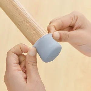 Grey silicone chair leg protector installed on a wooden furniture leg for silent floor protection