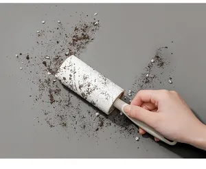 Detailed view of handheld lint roller effectively cleaning debris from a gray surface