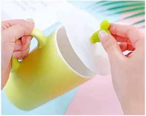Detail view of a green cactus silicone cup lid being lifted from a light green mug