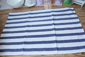 Detailed view of a Japanese style blue and white striped linen placemat on a wooden table