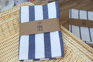 Close-up of blue and white striped linen napkins folded with kraft paper band on wicker tray