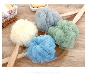 Close-up detail of colorful PE mesh bath loofahs with natural long wooden handles for exfoliating