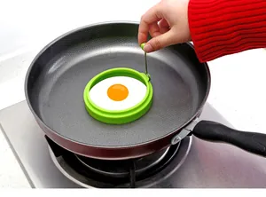 High-quality green circular silicone egg mold with handle for perfect fried eggs in a pan